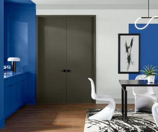 modern dining space with bold blue walls, dark green doors, white walls