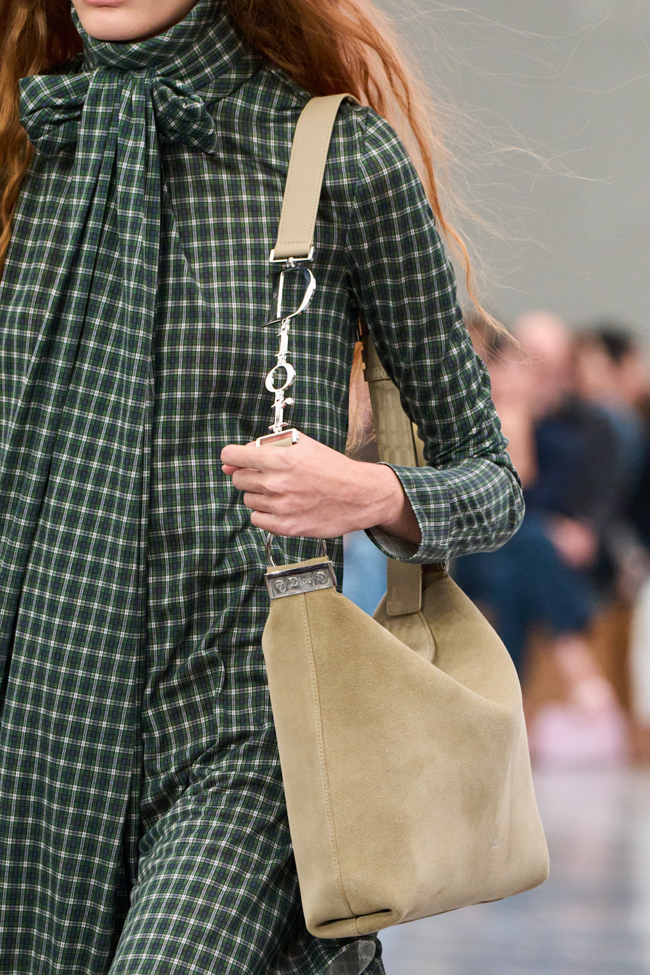 a model carries the dior diorly bag on the runway.