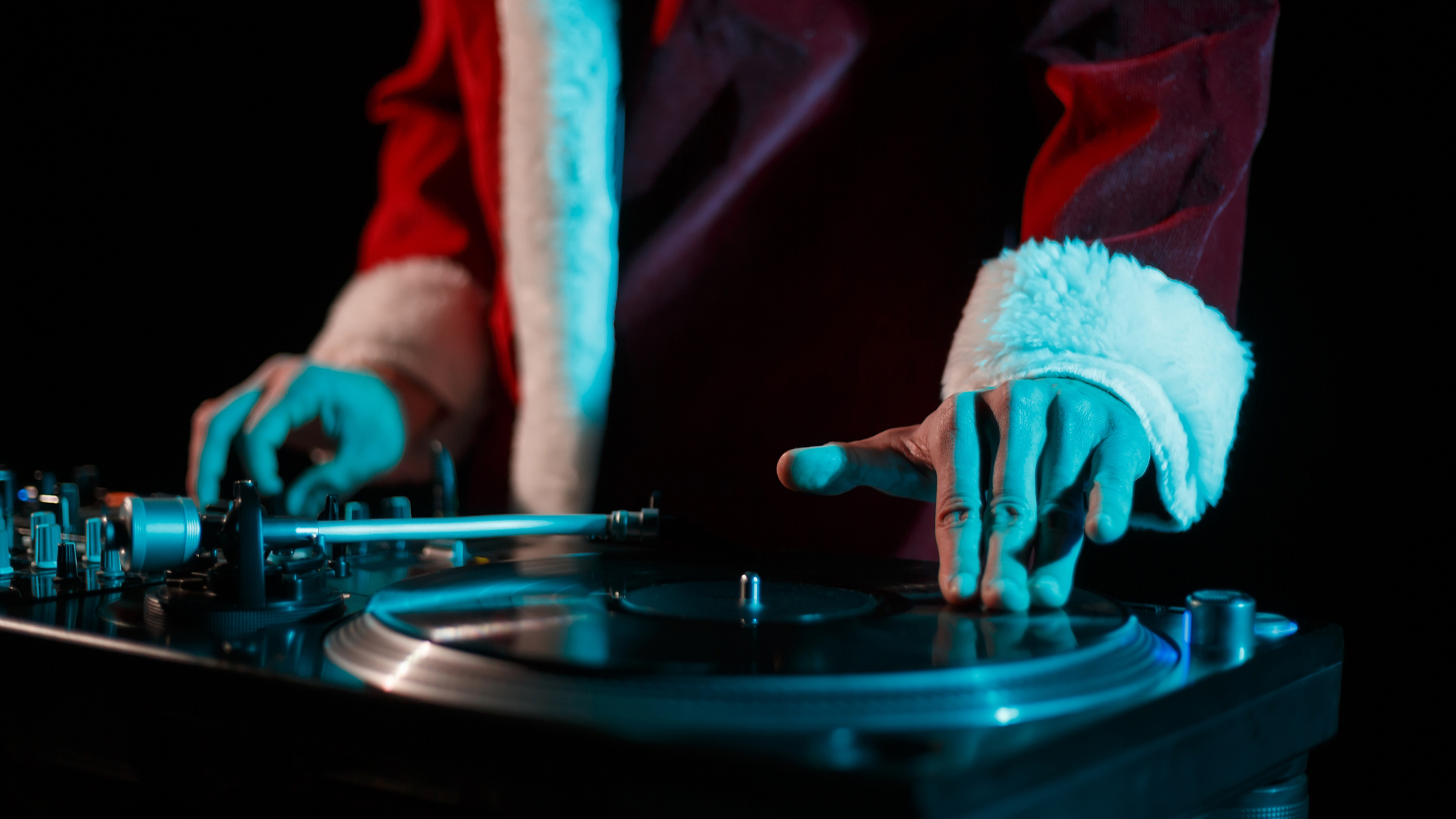 Man dressed as Father Christmas with his left hand on a vinyl deck