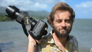 AFP photographer Jerome Brouillet poses for a picture with his camera on a beach a few kilometers from Teahupo'o, on the French Polynesian Island of Tahiti, on July 30, 2024.