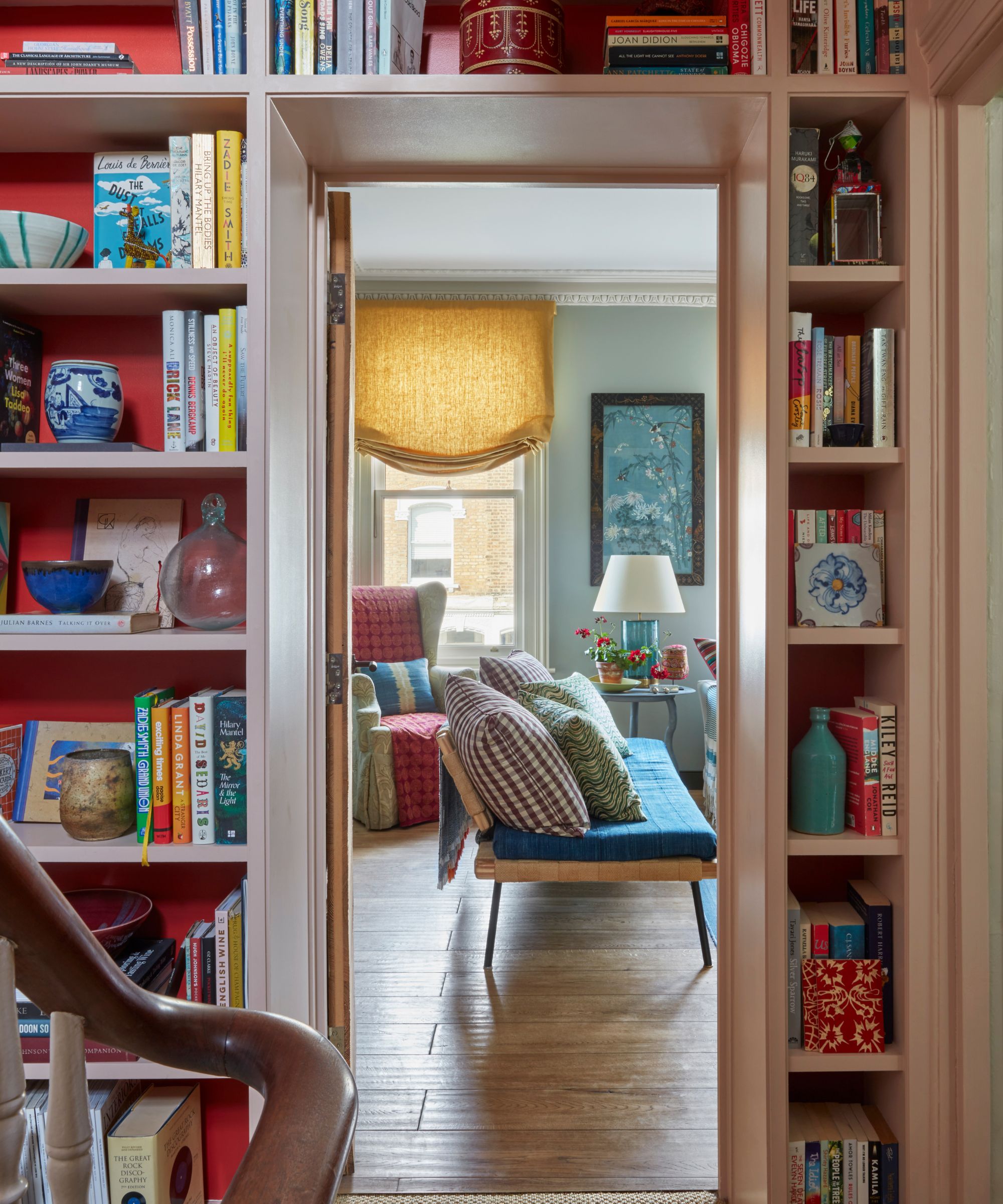 An eclectic bookcase surrounding a doorway into a living room