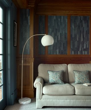 living room with dark blue walls, cream sofa and floor lamp