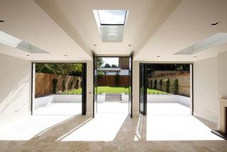 Floor-to-ceiling bi-fold doors and a rooflight fill this sunroom by IQ Glass