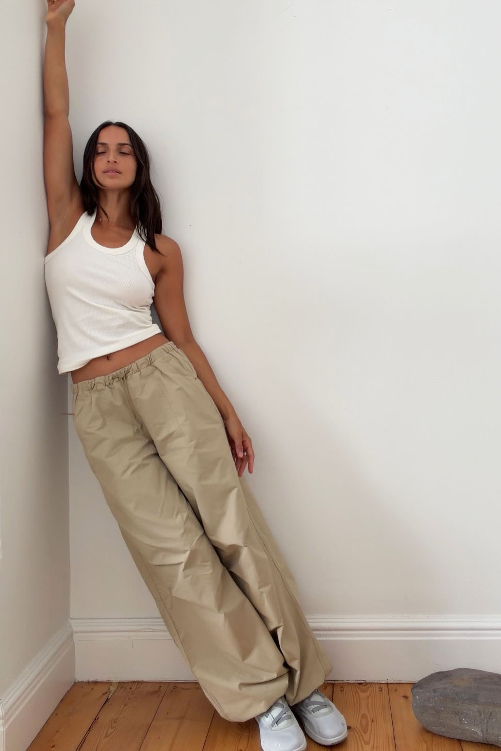 a woman wearing a white tank top, khaki pants, and white jeans