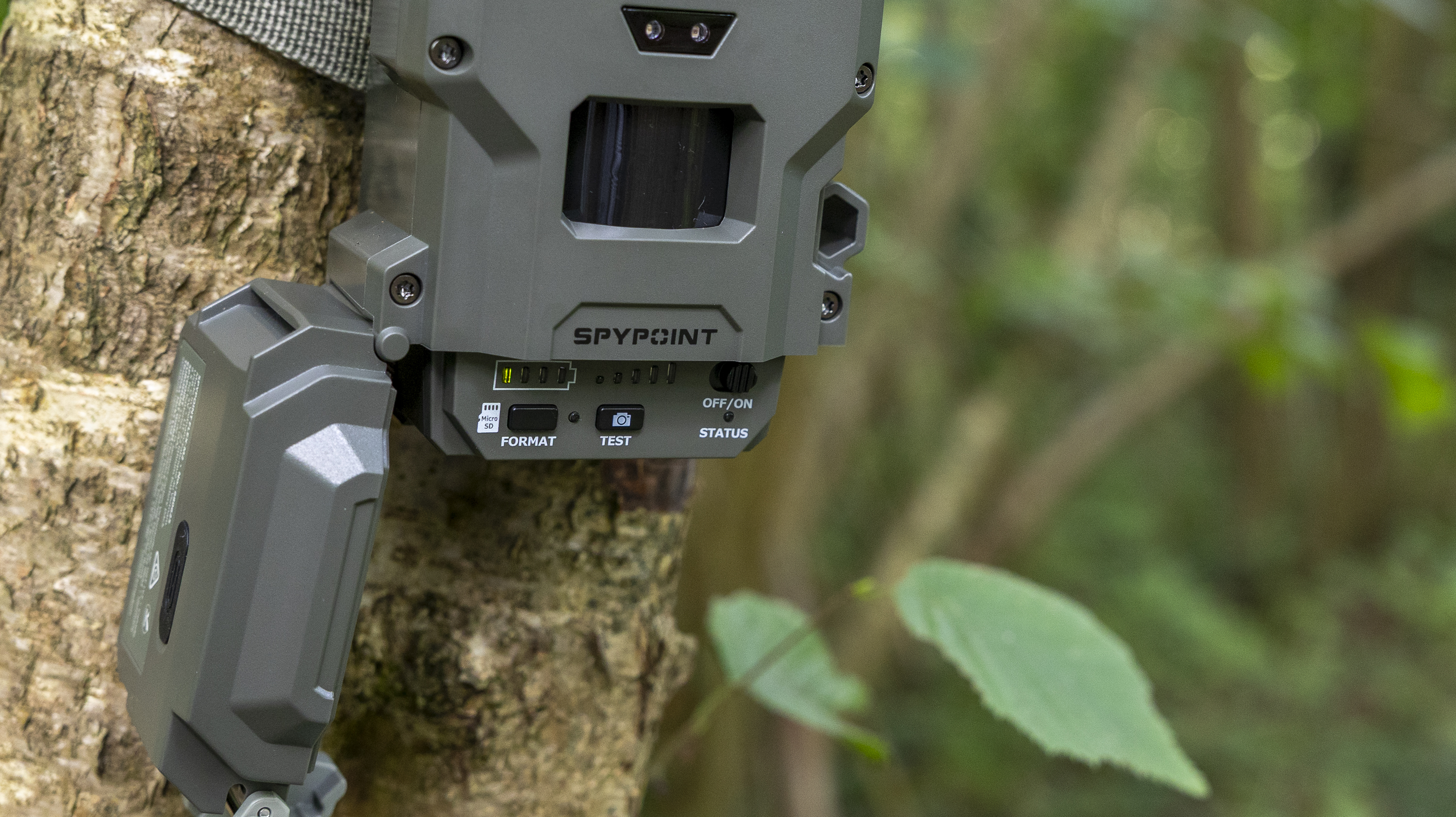 A close-up of the Spypoint FLEX-M2 trail camera opened up and attached to a tree