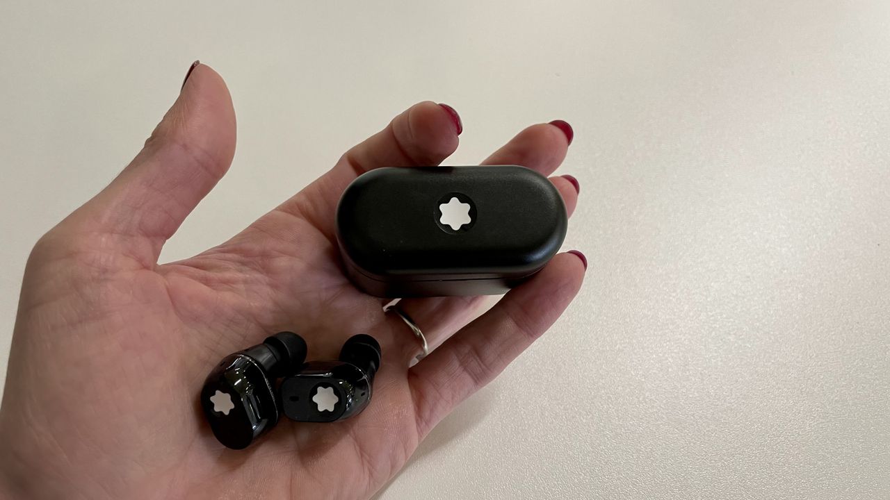 Montblanc MTB 03 earbuds and case, held in a hand on white background