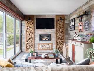 Man cave with large TV with log pile effect wall panels and in built wood burning stove