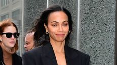 Zoe Saldana wearing a coat and gold hoop earrings