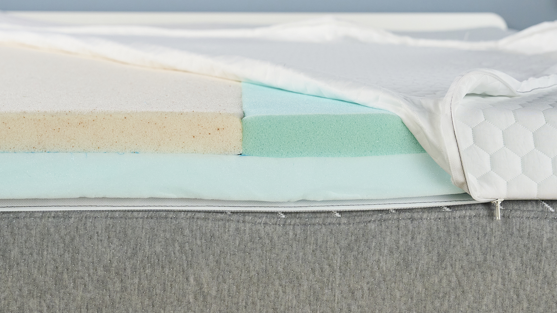 We remove the cover of the Helix Dual Comfort Mattress Topper to reveal the two different foams (pale yellow on left, and mint-green on the right) used to accommodate couples with different firmness preferences. 