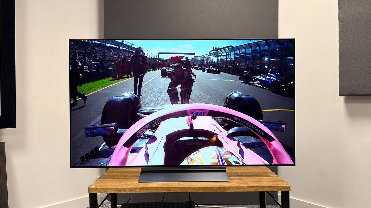 The LG C5 55-inch OLED TV on a table, seen straight-on. On screen is a still from Netflix's Drive To Survive, from inside a Formula One driver's cockpit.