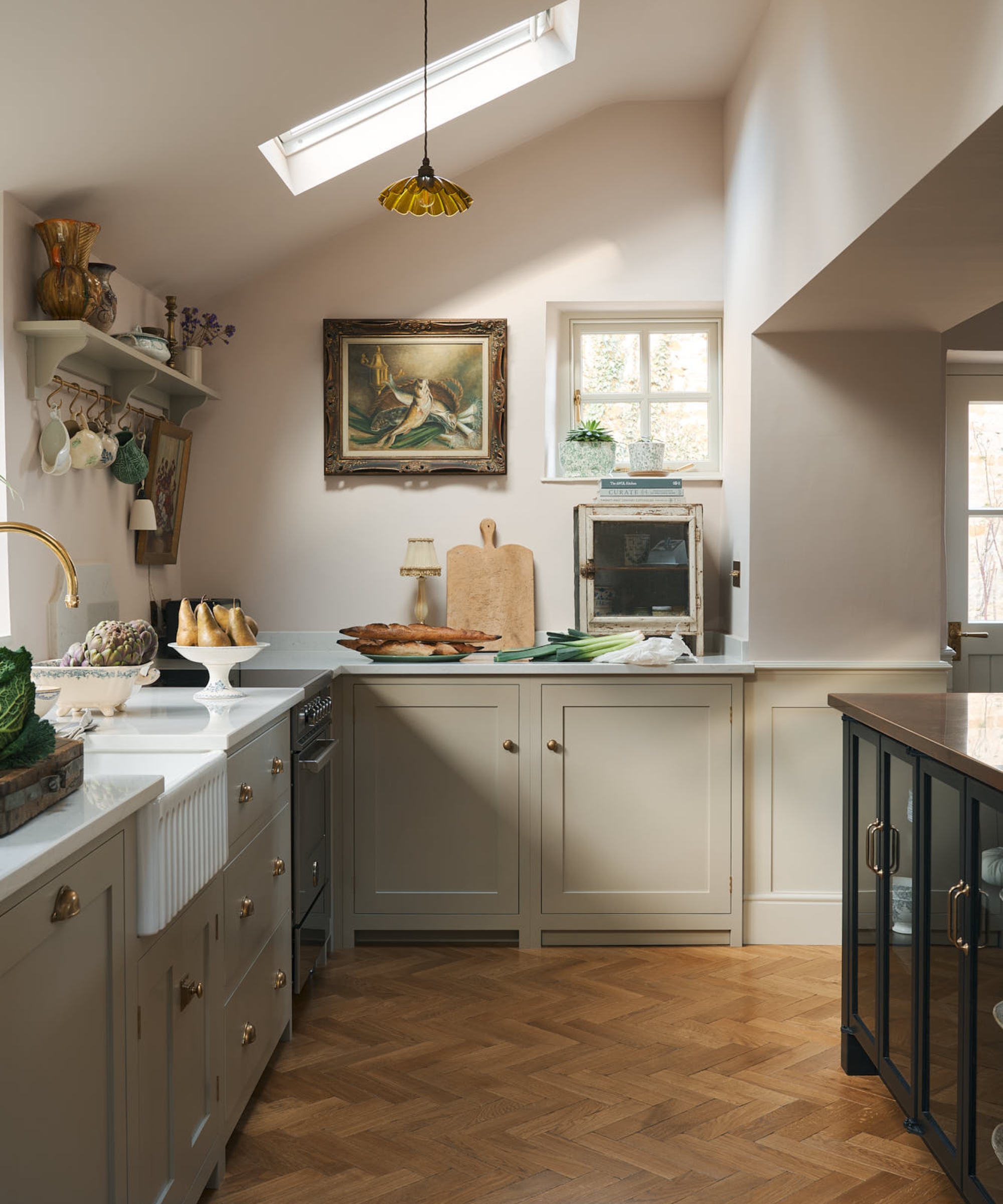 A neutral kitchen with mushroom cabinets, soft pink walls, and white countertops