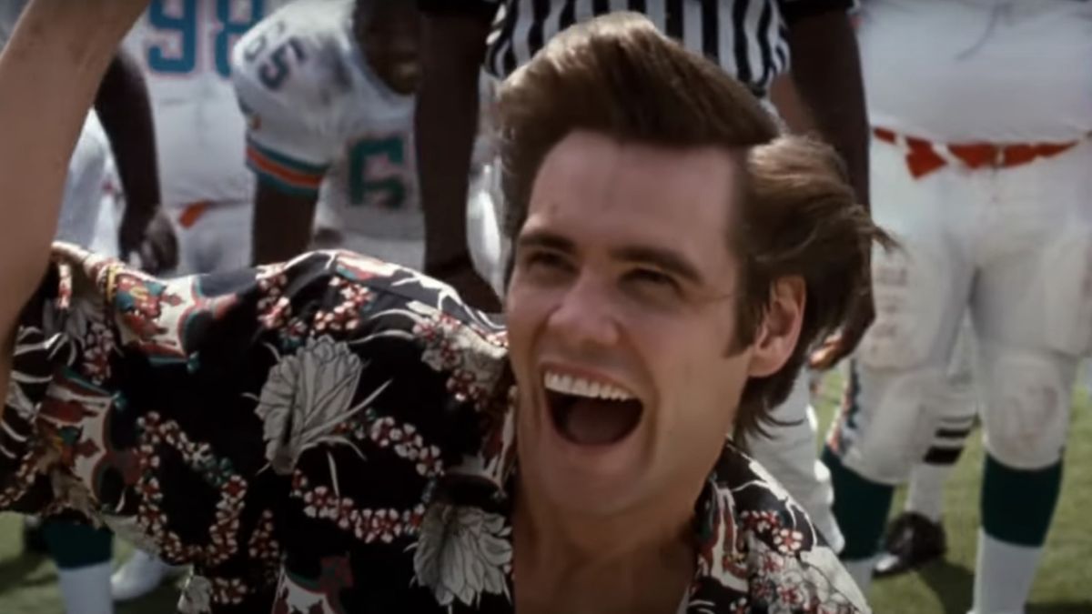 Jim Carrey smiling on the football field in Ace Ventura: Pet Detective