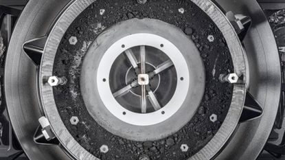 View of the OSIRIS-REx Touch-and-Go-Sample-Acquisition-Mechanism (TAGSAM) head with lid removed, unveiling the bulk of asteroid Bennu sample inside.