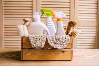 A wooden cleaning caddy filled with eco cleaning products.
