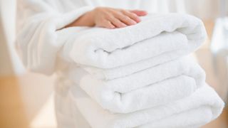 women holding stack of white towels to support a guide to signs your towels need replacing