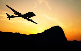 A military drone flying over mountains on sunset background