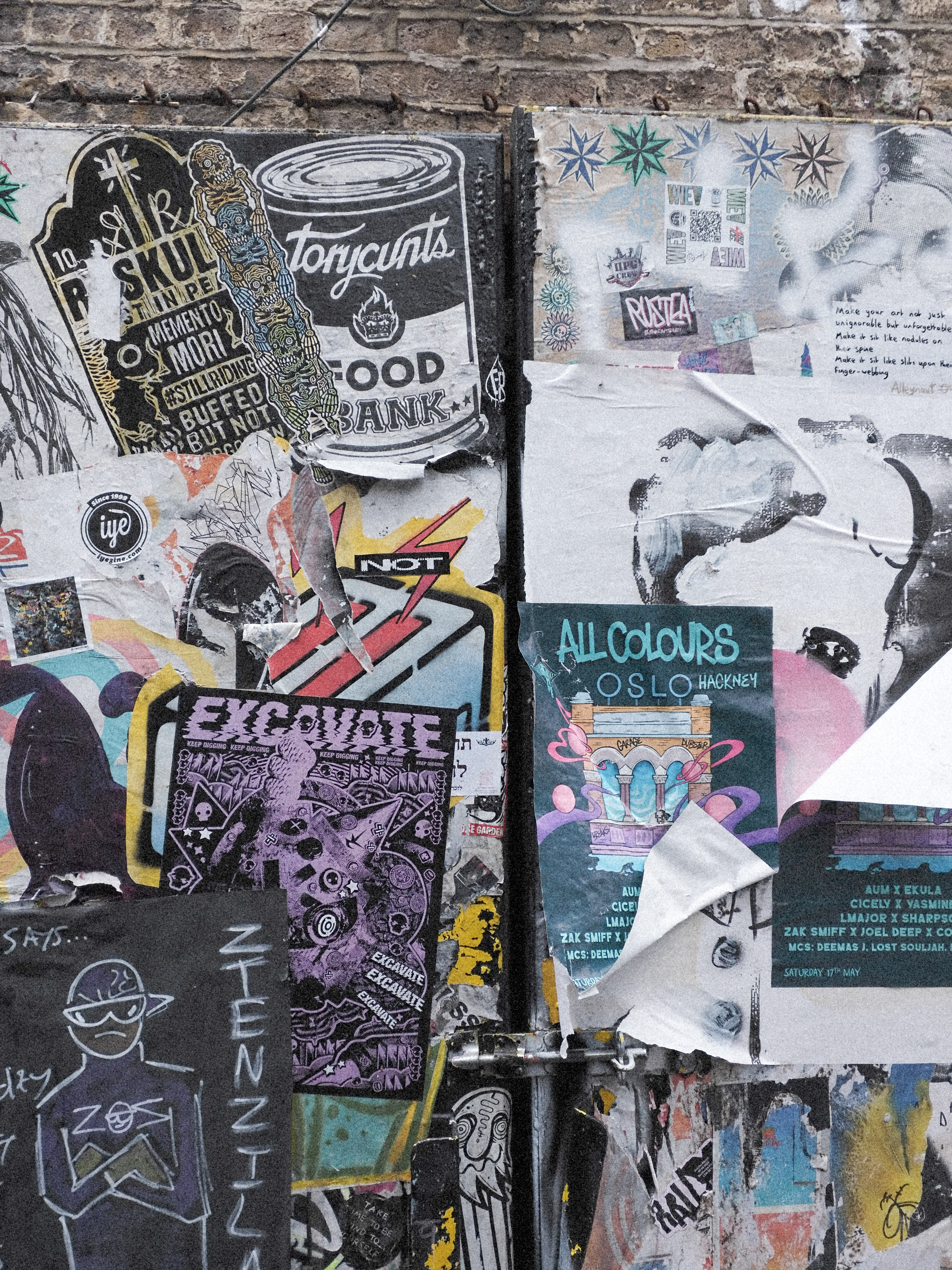 Posters plastered over one another on a brick wall