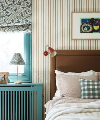 colorful bedroom with stripe wallpaper and upholstered headboard and blind