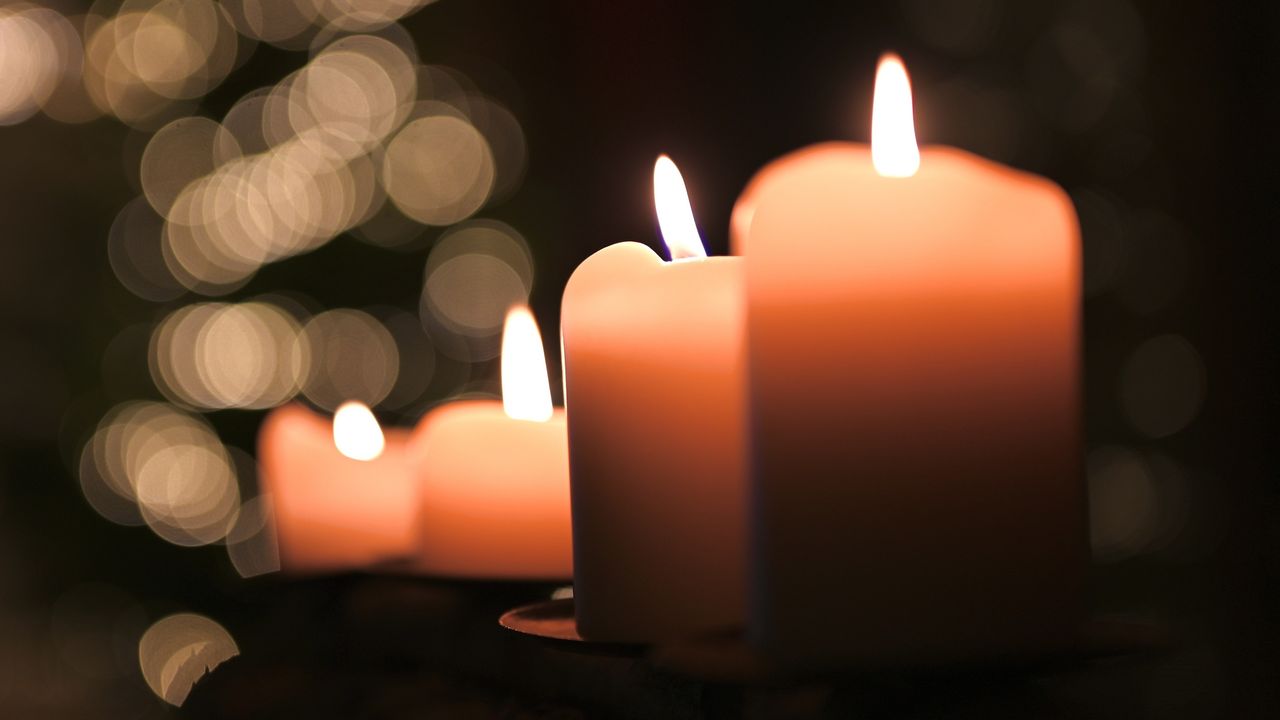 Lighted candles that look like they&#039;re in a funeral setting.