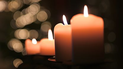 Lighted candles that look like they're in a funeral setting.