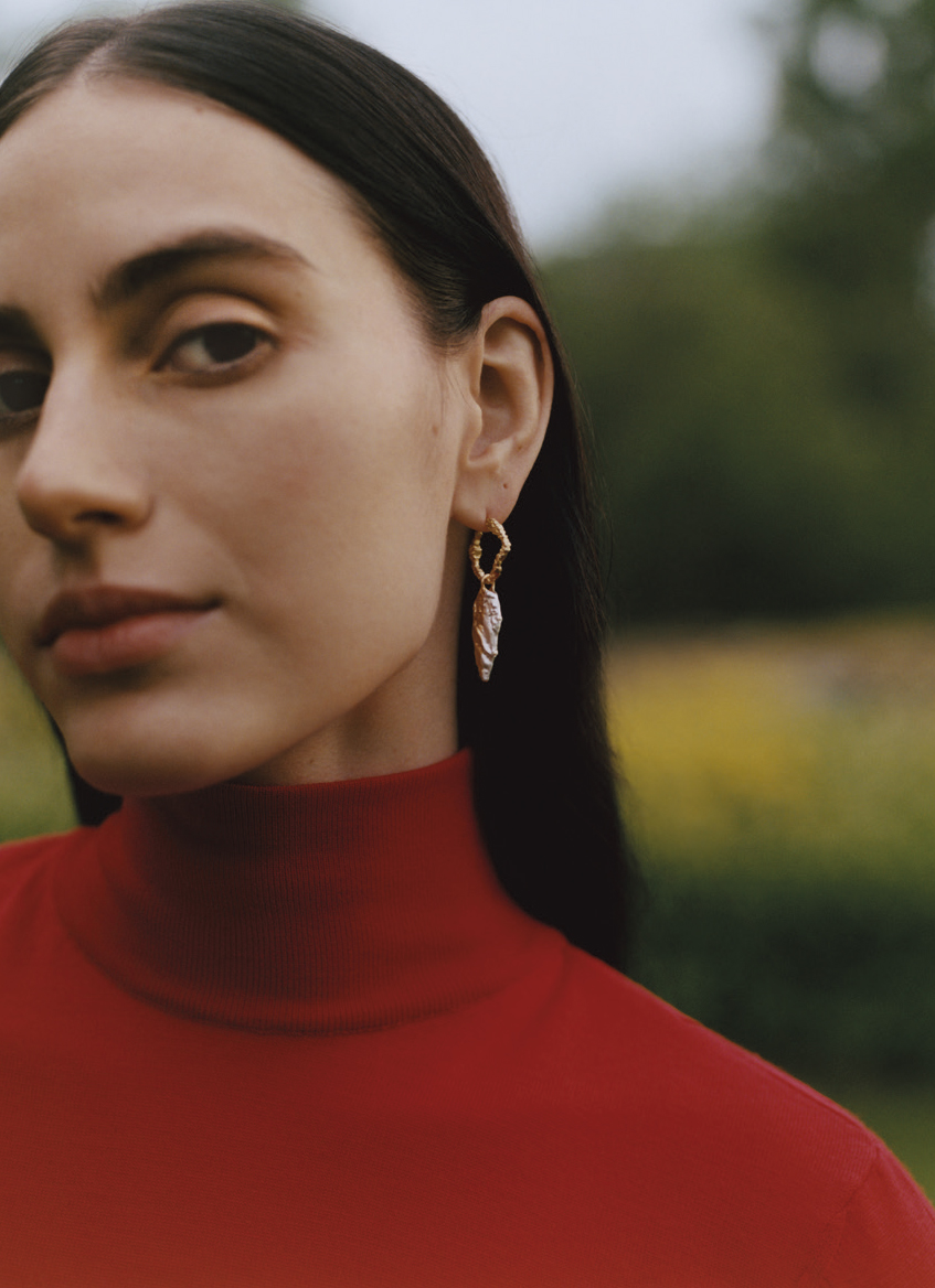 woman wearing necklace and earrings stood outside
