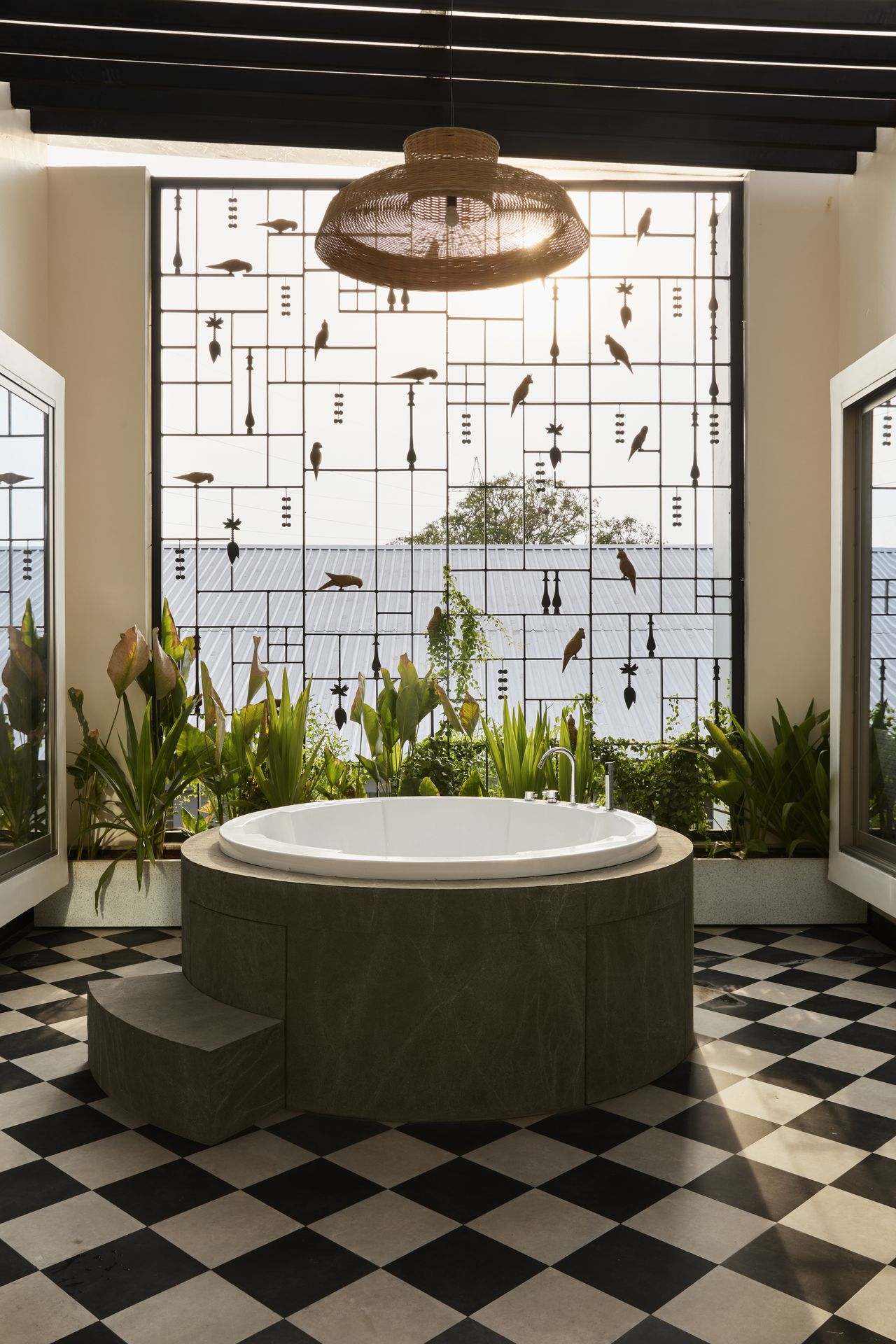 A bathroom with chequerboard flooring, a lighting piece above a round bathtub