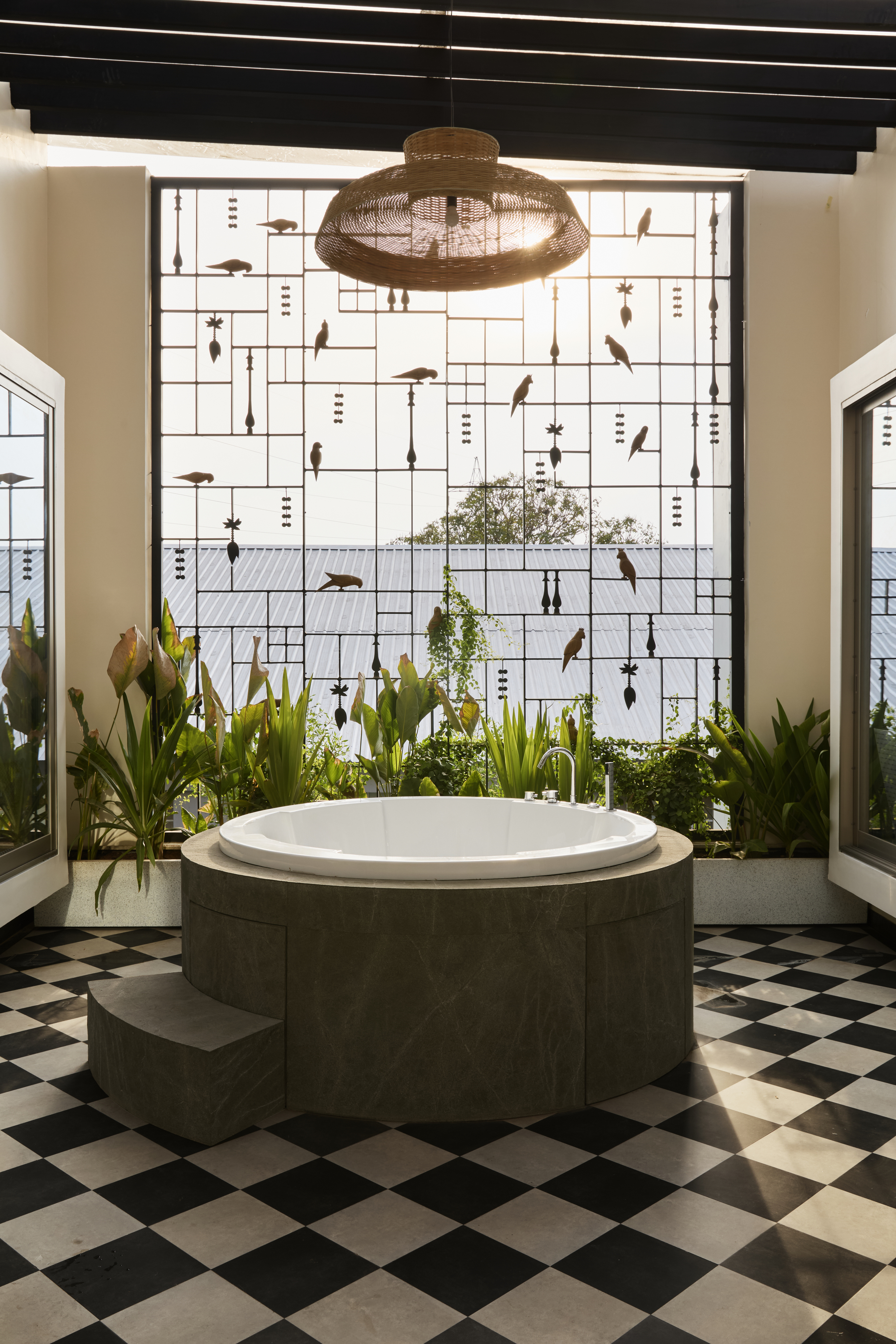 A bathroom with chequerboard flooring, a lighting piece above a round bathtub