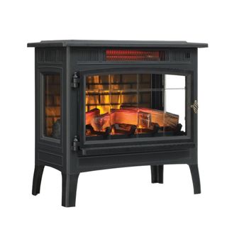 A black freestanding fireplace with logs in it