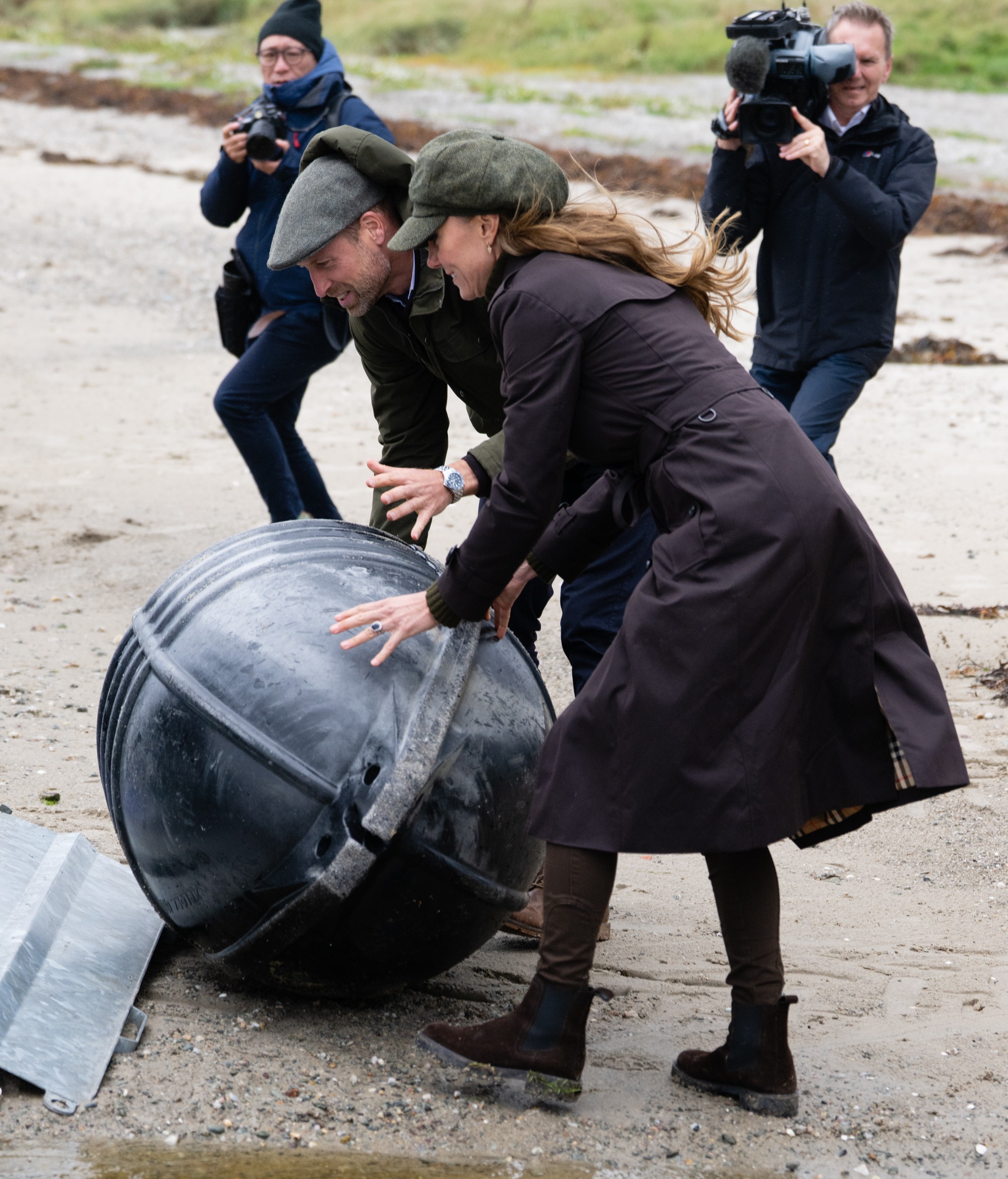 Prince William and Princess Kate pushing a barrel on the beach
