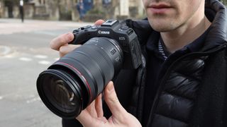 man holding Canon EOS R8 mirrorless digital camera and lens