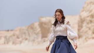 Moiraine in a white shirt and blue skirt channeling the One Power on a beach in The Wheel of Time season 2