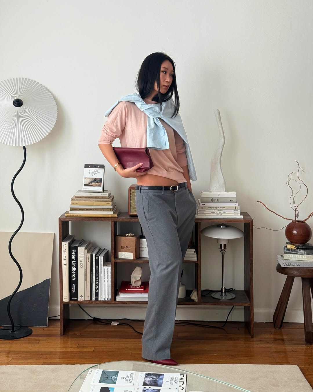 A woman wearing soft pink top and ice blue button-down around her shoulders, one of the biggest 2026 spring color pairings.