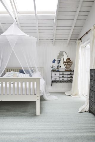 white bedroom with painted shiplap walls and ceiling, stripe carpet, vintage pieces, white painted bed, muslin canopy, blue desk lamp, mirror