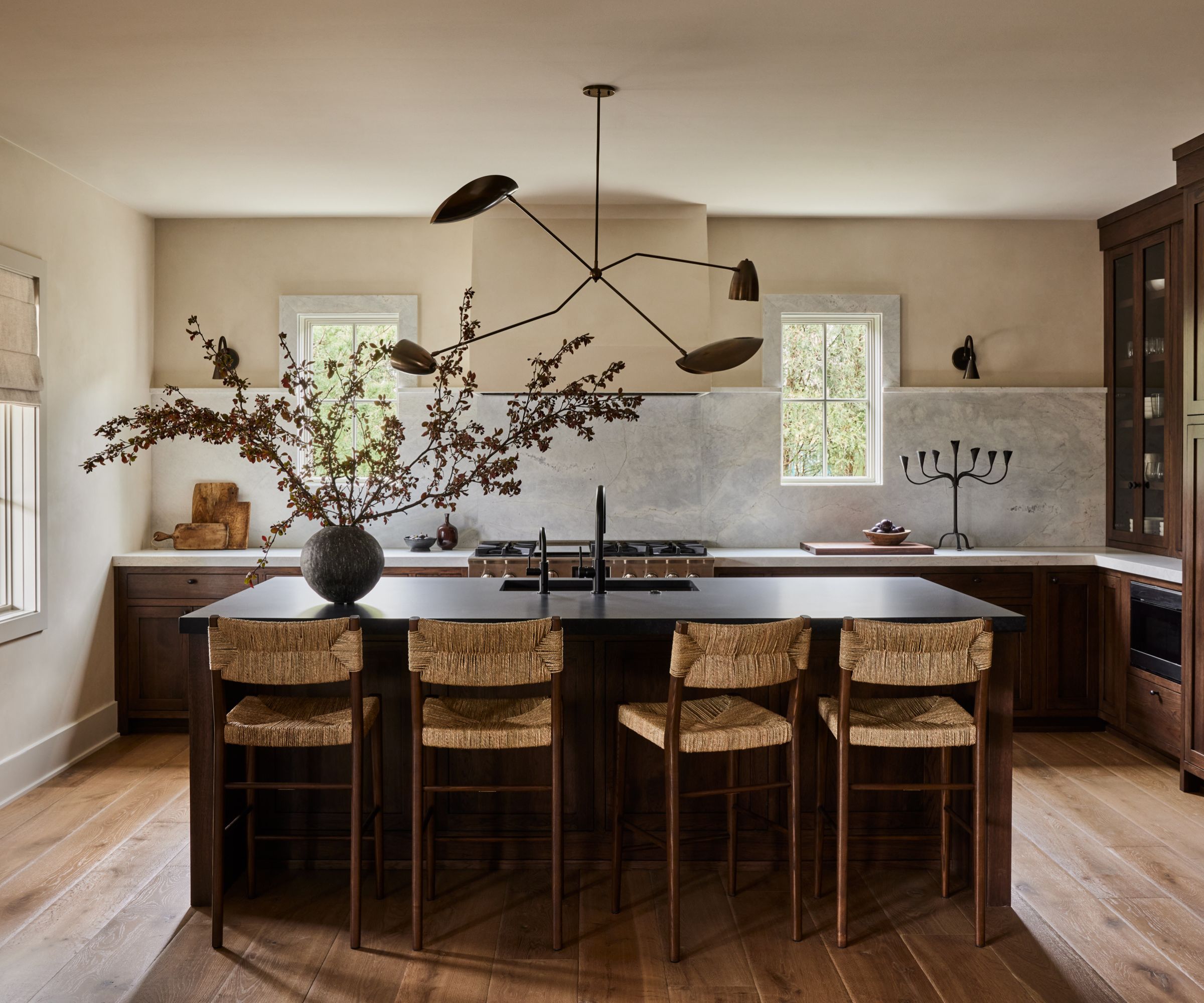 A dark wood kitchen with a marble countertop and backsplash and warm white walls