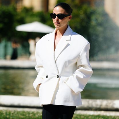 A paris fashion week attending wearing sunglasses and white oversized blazer