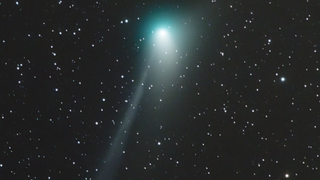 a green comet against a backdrop of stars