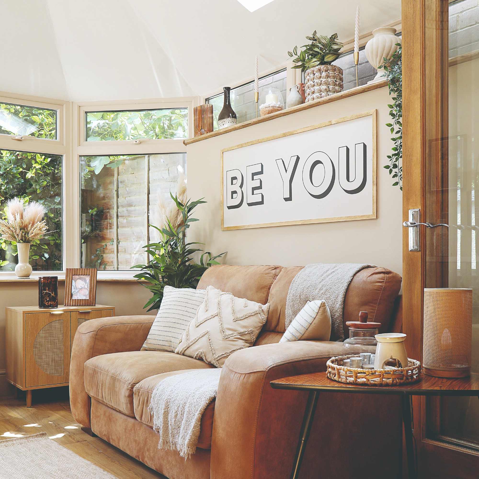 A neutral living room with taupe walls, a sloped white ceiling and a light brown leather sofa