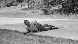 2NCN6G2 Civil rights activist James Meredith grimaces in pain as he pulls himself across Highway 51 after being shot in Hernando, Miss., June 6, 1966. Meredith, who defied segregation to enroll at the University of Mississippi in 1962 completed the march from Memphis, Tenn., to Jackson, Miss., after treatment of his wounds. (AP Photo/Jack Thornell)