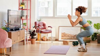 A woman doing a bodyweight squat in her living room at home