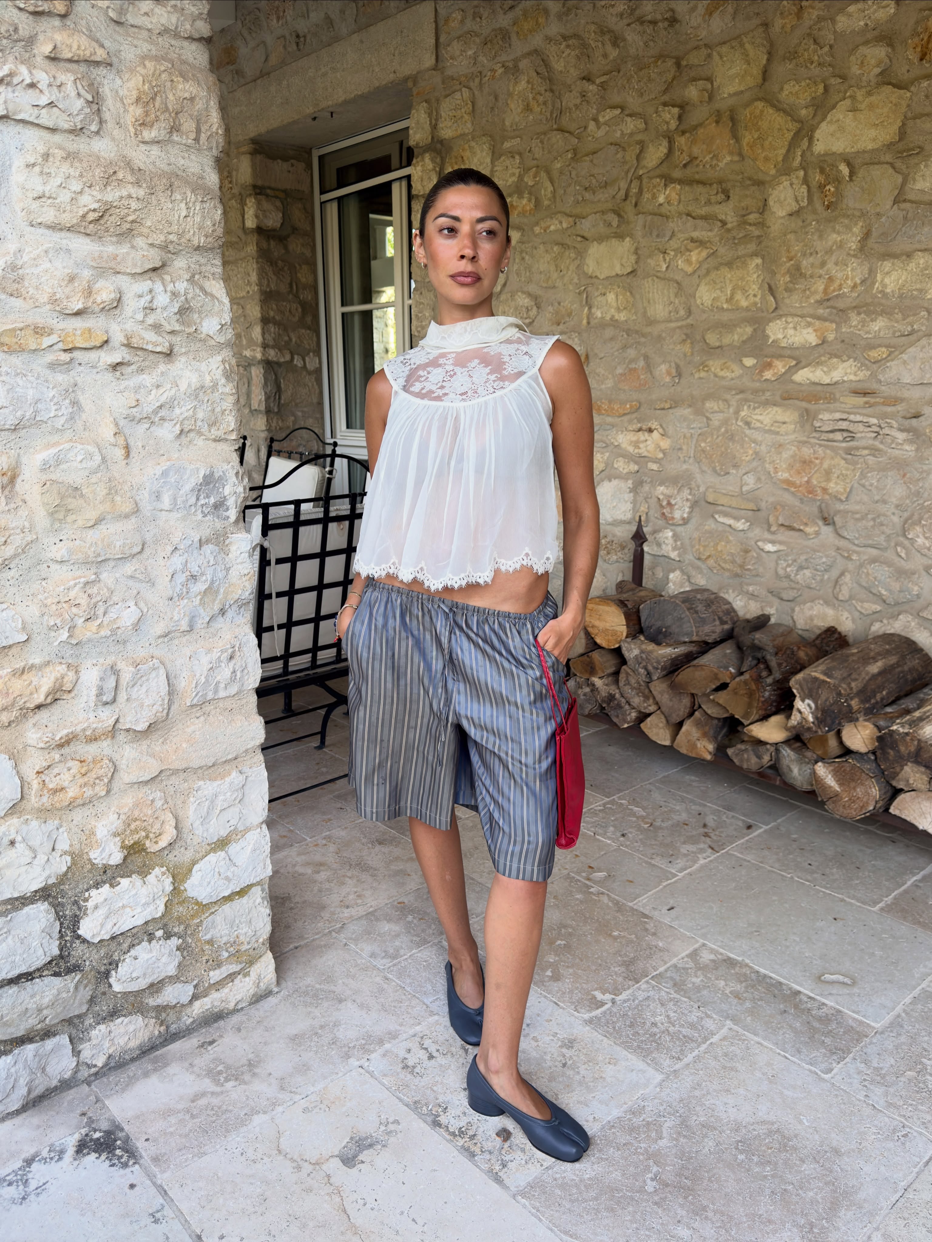 An image of @smythsisters wearing a lace-trim top with low-rise elasticated shorts and black ballet flats.