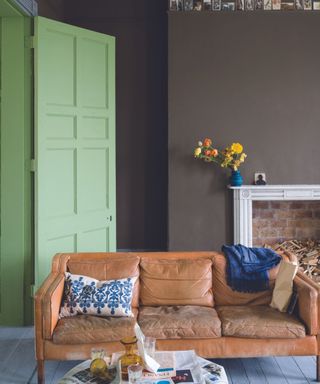 living room with brown walls, tan leather sofa and green door