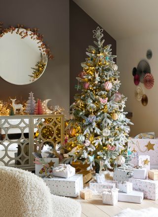 frosted Christmas tree with pastel decorations,, taupe wall, mirrored sideboard, presents