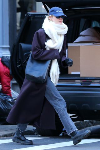 Gigi Hadid walks in Soho Manhattan wearing a purple overcoat and a fluffy scarf with gray jeans and lug sole boots