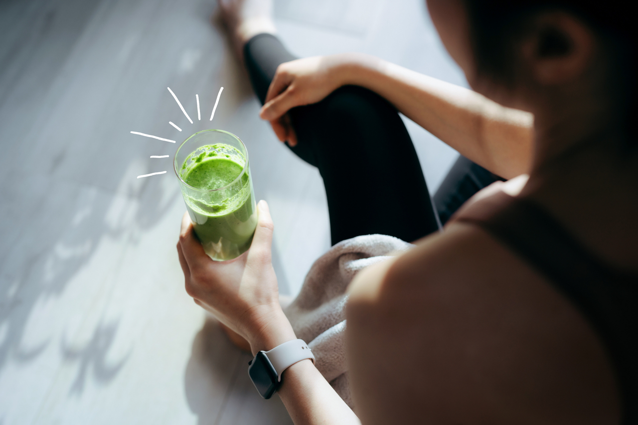 Woman drinking a green juice sitting down on the floor, one of the components of a liver detox