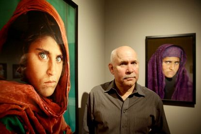 Photographer Steve McCurry stands in front of his portraits of Shabbat Gula.