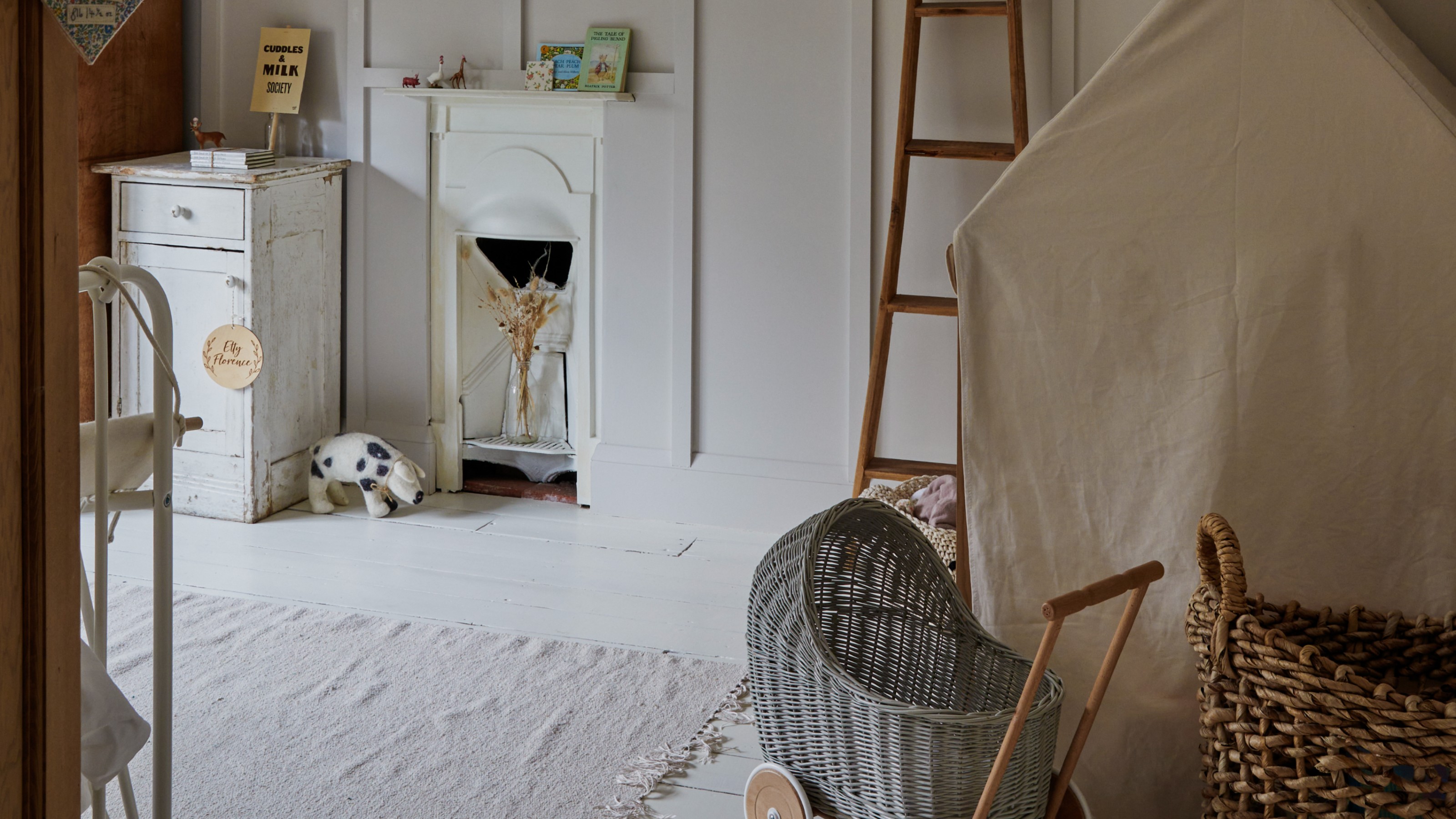 A neutral playroom with a play tent, a straw play stroller and a neutral rug on the floor 