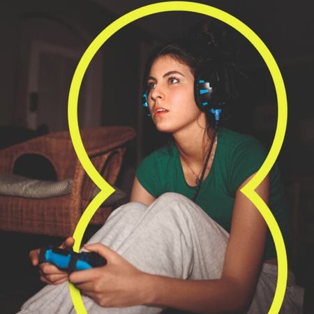A woman playing a video game with a headset on in a dark room