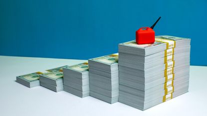 stacks of money with a small gas can on top of the largest pile