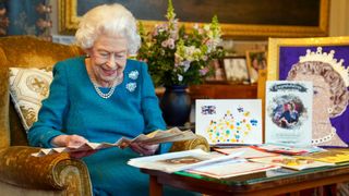 Queen Elizabeth II looks at a fan as she views a display of memorabilia from her Golden and Platinum Jubilees