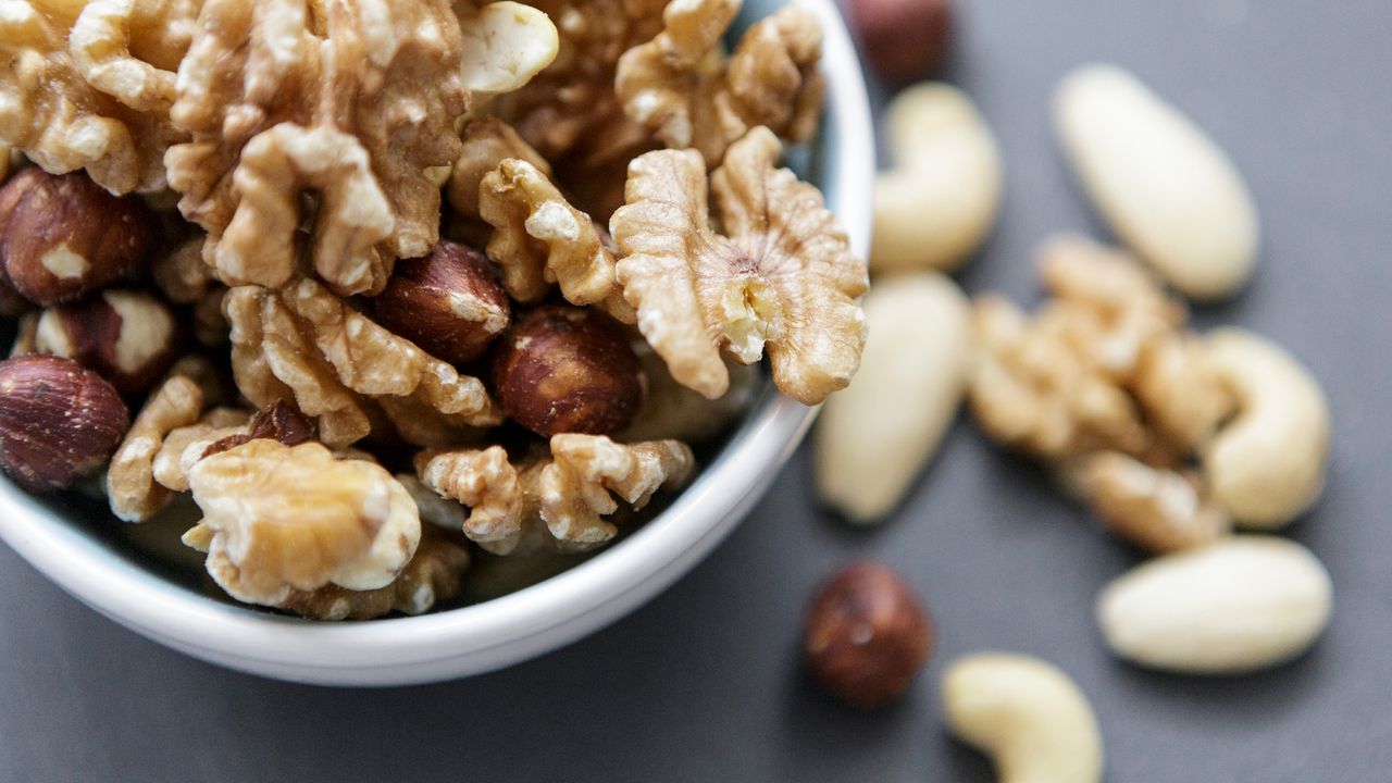 A bowl of mixed nuts overflows onto a table